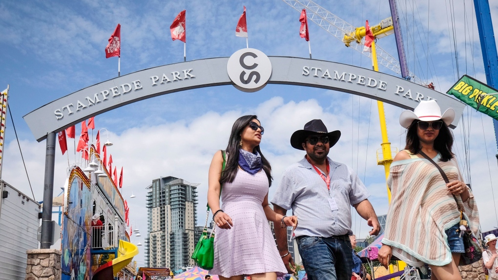 Visitors walk along the midway at the Calgary Stampede in Calgary, Saturday, July 8, 2017. THE CANADIAN PRESS/Jeff McIntosh