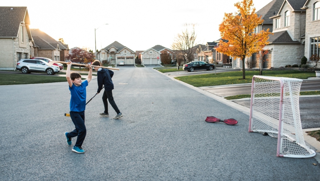 Two boys playing street hockey on a residential street in the fall. (Getty Images)