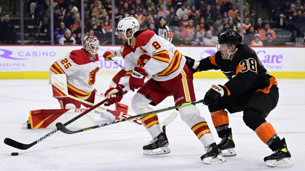 The Calgary Flames' Chris Tanev plays a loose puck past the Philadelphia Flyers' Patrick Brown during the second period in Philadelphia on Nov. 21, 2022. (AP Photo/Derik Hamilton)