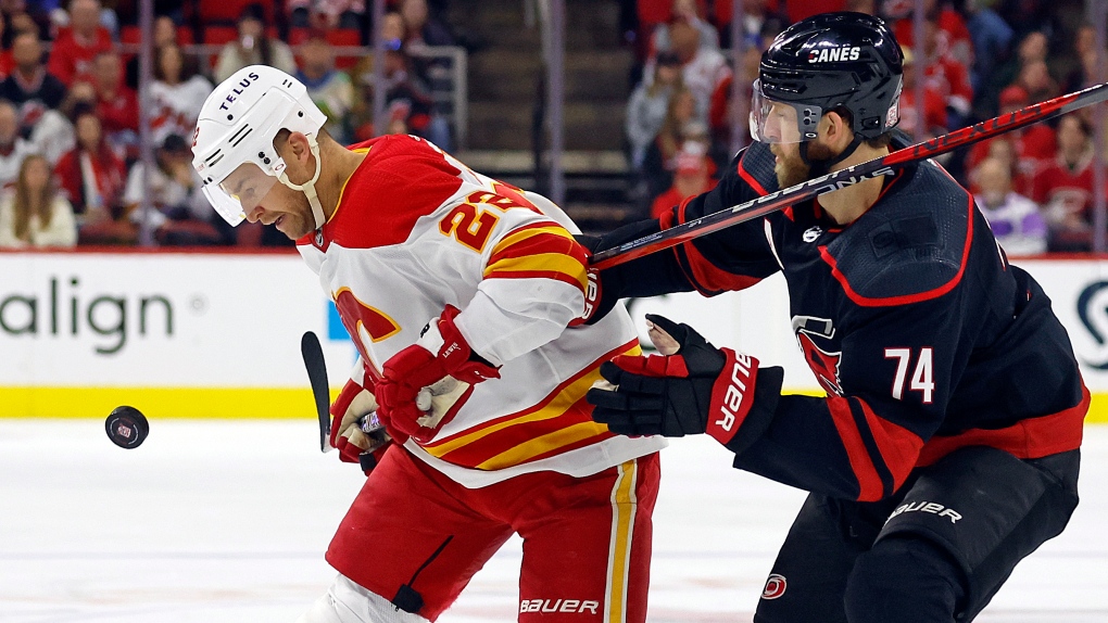 Calgary Flames' Trevor Lewis (22) tries to control the puck in front of Carolina Hurricanes' Jaccob Slavin (74) during the third period of an NHL hockey game in Raleigh, N.C., Saturday, Nov. 26, 2022 (AP Photo/Karl B DeBlaker).