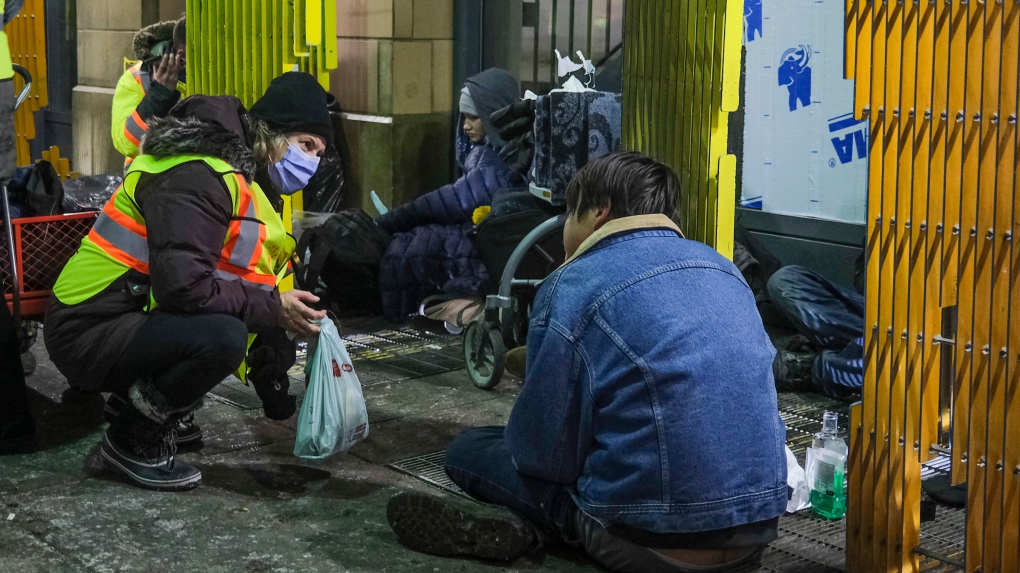 An outreach volunteer offers help to the homeless on a -20C night in Calgary, Alta., Tuesday, Dec. 14, 2021. THE CANADIAN PRESS/Jeff McIntosh
