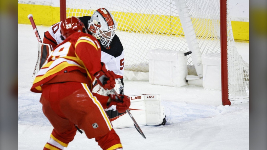 New Jersey Devils goalie Nico Daws, right, looks back as Calgary Flames' Dillon Dube scores during second period NHL hockey action in Calgary, Wednesday, March 16, 2022.(THE CANADIAN PRESS/Jeff McIntosh)