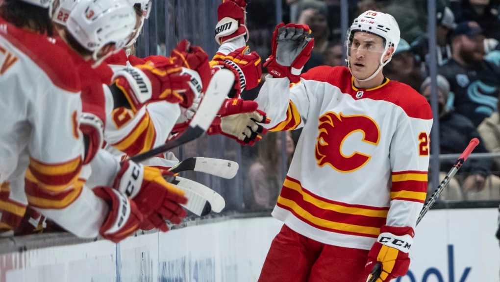 Calgary Flames defenseman Michael Stone is congratulated by teammates on the bench after scoring a goal during the second period of an NHL hockey game against the Seattle Kraken, Saturday, April 9, 2022, in Seattle. (AP Photo/Stephen Brashear)