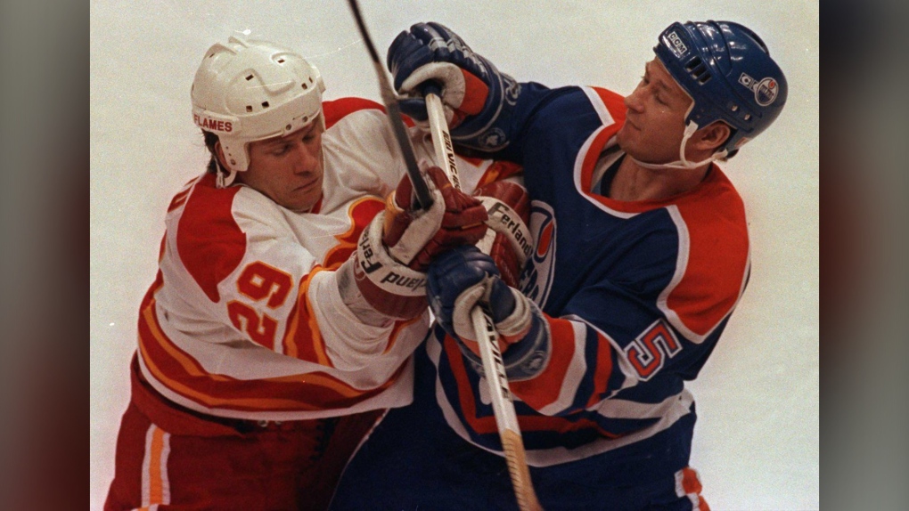 Calgary Flames' Joel Otto (left) jousts with Edmonton Oilers' Steve Smith during NHL playoff action in Calgary, Apr.16, 1991. (CP PICTURE ARCHIVE-Mike Ridewood)