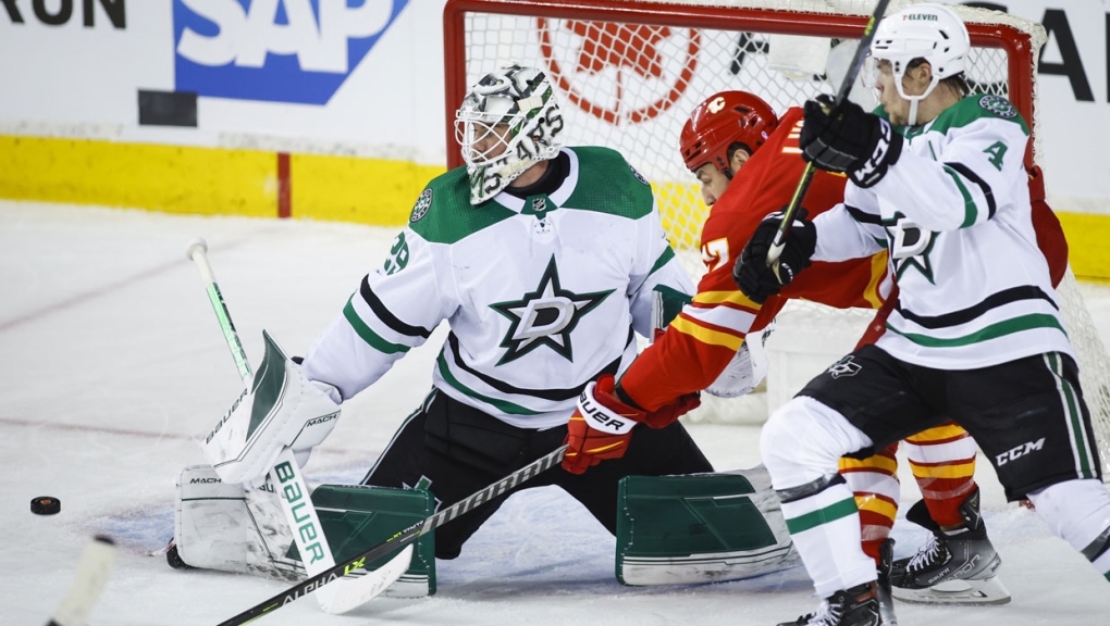 Dallas Stars goalie Jake Oettinger, left, kicks the puck away from Calgary Flames left wing Milan Lucic, centre, as Flames' Miro Heiskanen defends during second period NHL playoff hockey action in Calgary, Thursday, May 5, 2022.THE CANADIAN PRESS/Jeff McIntosh