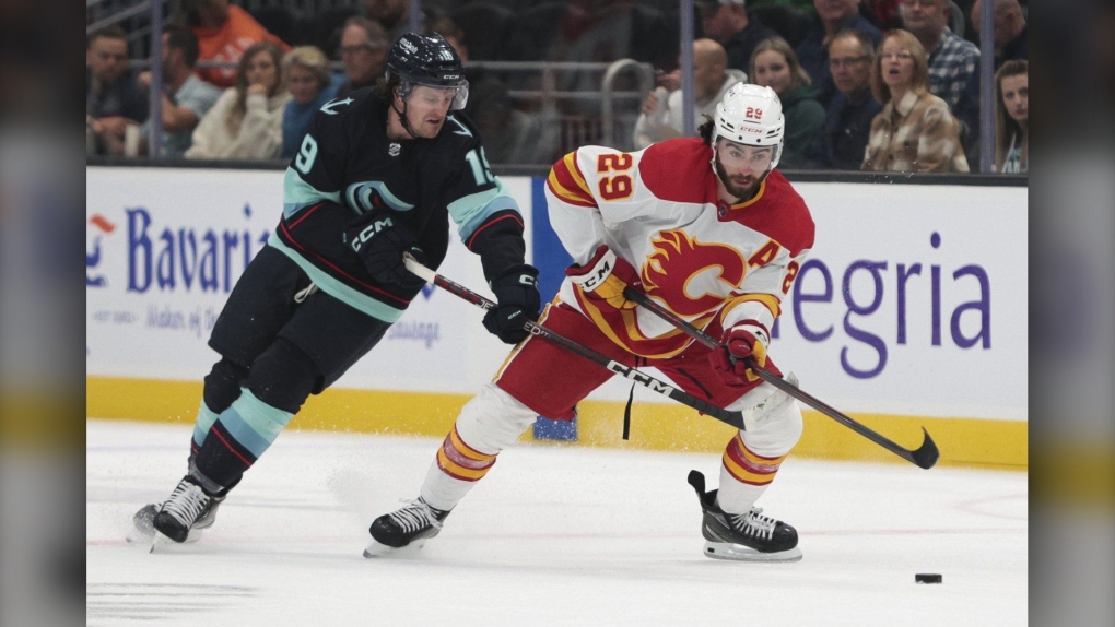 Calgary Flames center Dillon Dube (29) moves the puck as Seattle Kraken center Jared McCann defends during the first period of a preseason NHL hockey game Tuesday, Sept. 27, 2022, in Seattle. (AP Photo/Jason Redmond)