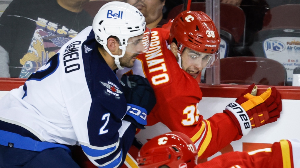 Winnipeg Jets defenceman Dylan DeMelo, left, checks Calgary Flames forward Matthew Coronato during third period NHL preseason hockey action in Calgary, Alta., Monday, Oct. 2, 2023. THE CANADIAN PRESS/Jeff McIntosh
