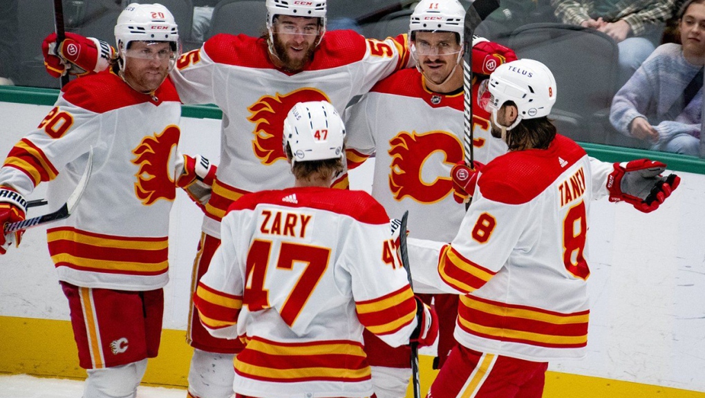Calgary Flames player gather with Calgary Flames centre Mikael Backlund (11) after he scored a goal during the third period of an NHL hockey game against the Dallas Stars, Friday, Nov. 24, 2023, in Dallas. (AP Photo/Emil T. Lippe)