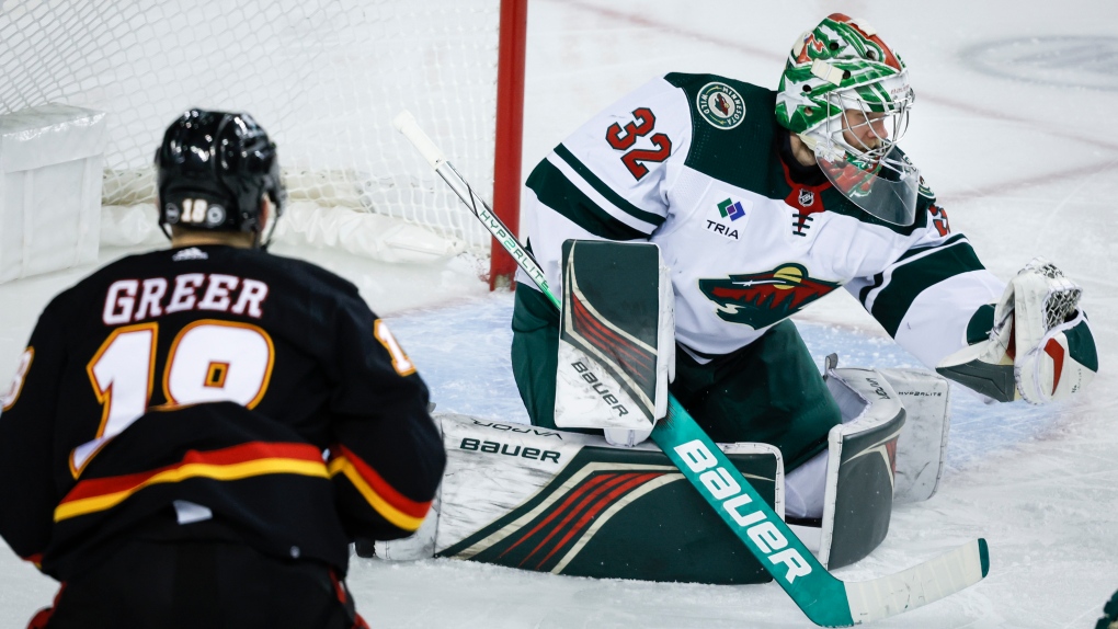 Minnesota Wild goalie Filip Gustavsson, right, grabs the puck as Calgary Flames forward A.J. Greer looks on during third period NHL hockey action in Calgary, Tuesday, Dec. 5, 2023.THE CANADIAN PRESS/Jeff McIntosh
