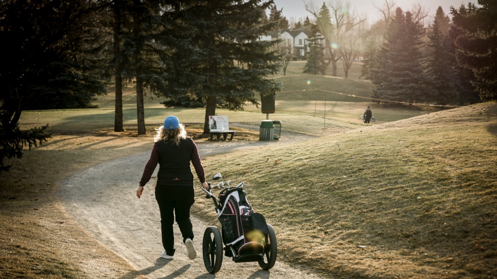 A golfer walks a cart path while playing a round at the Shaganappi Point golf course in Calgary, Tuesday, Dec. 5, 2023. Above average temperatures and a lack of snow has allowed some golf courses to open for play.  (THE CANADIAN PRESS/Jeff McIntosh)