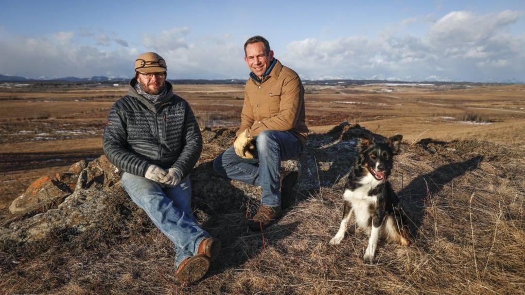 Justin Thompson, right, executive director of the Southern Alberta Land Trust, landowner Matt Kumlin and Kumlin's dog, Newt, look out over ranchland west of Cochrane, Alta., Friday, Feb. 10, 2023. THE CANADIAN PRESS/Jeff McIntosh