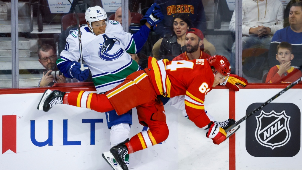 Vancouver Canucks' Dakota Joshua, left, is checked by Calgary Flames' Ben Jones during first period NHL preseason hockey action in Calgary, Sunday, Sept. 24, 2023. (THE CANADIAN PRESS/Jeff McIntosh)